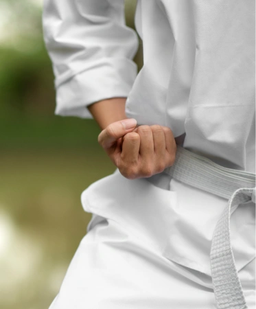 Close-up of a martial artist in a white uniform demonstrating a focused hand position during training.